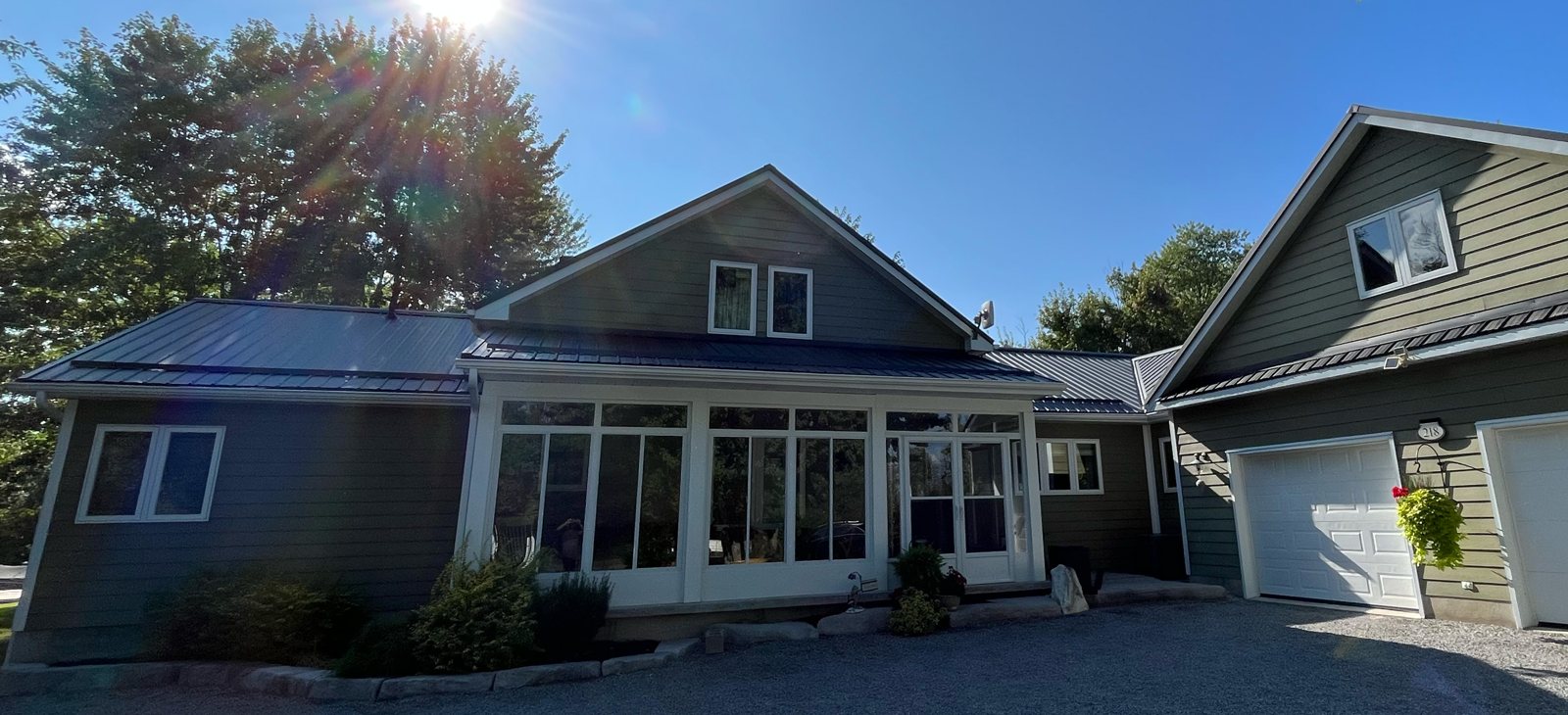 Steel roof catching sun over a lakeside home
