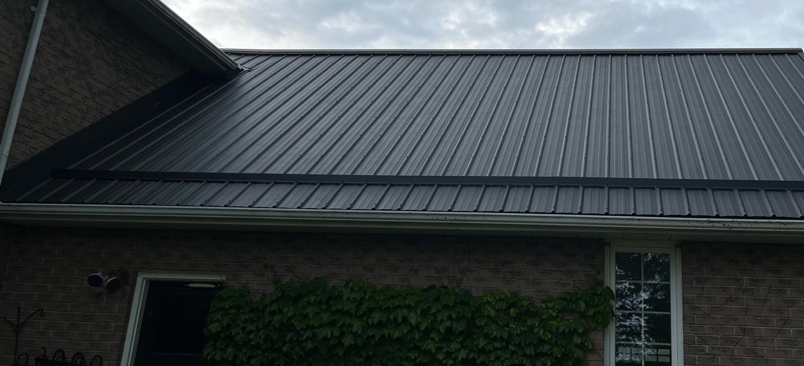 Low-slope steel roof over a brick house