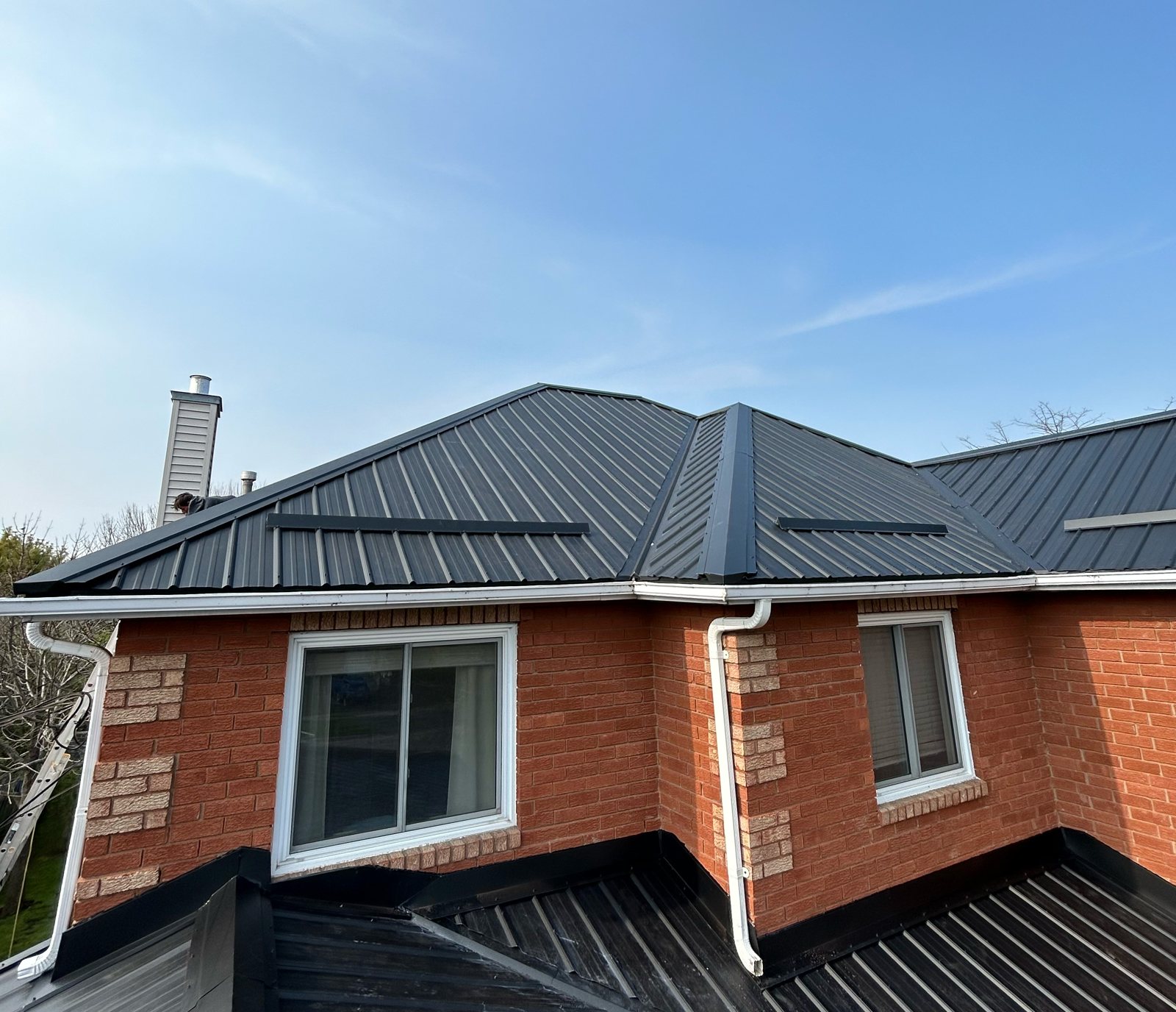 Dark steel roof over a red brick home