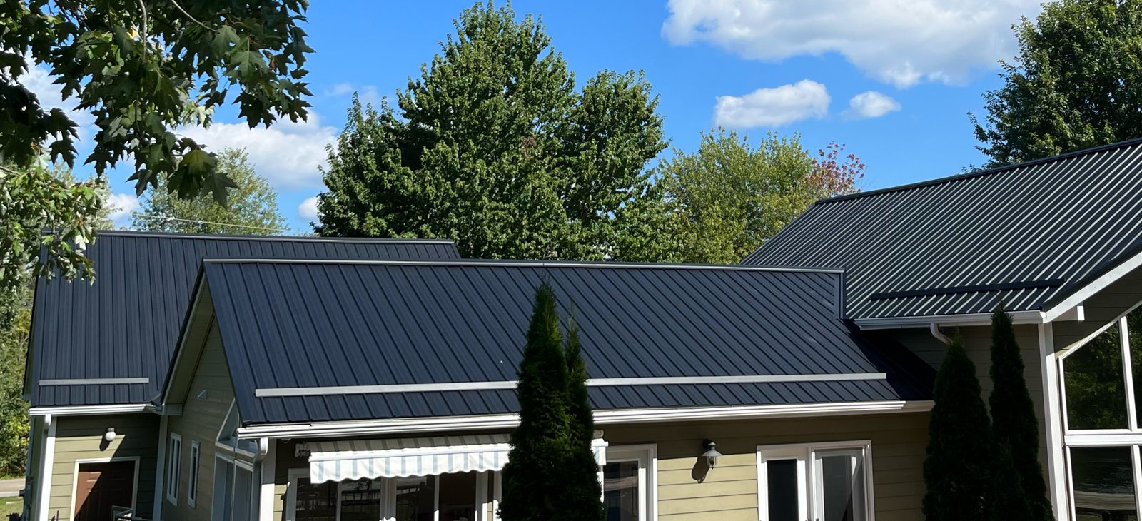 Charcoal standing seam roof on a country home with sunroom