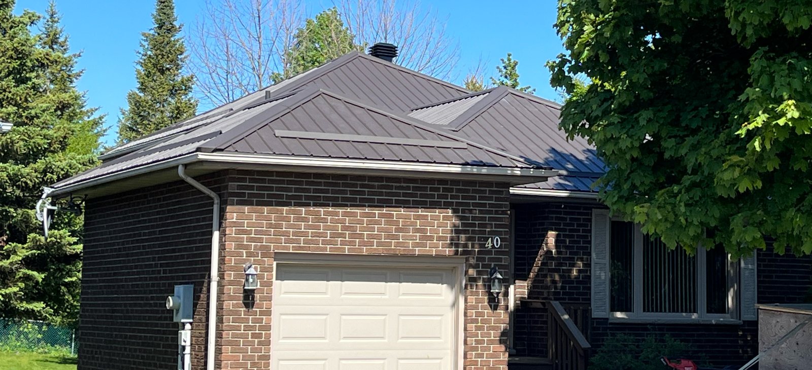 Brick garage and home with dark standing seam roof