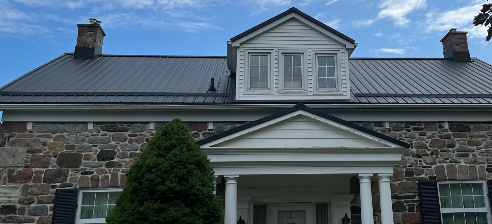 Dark steel roof on a stone century home